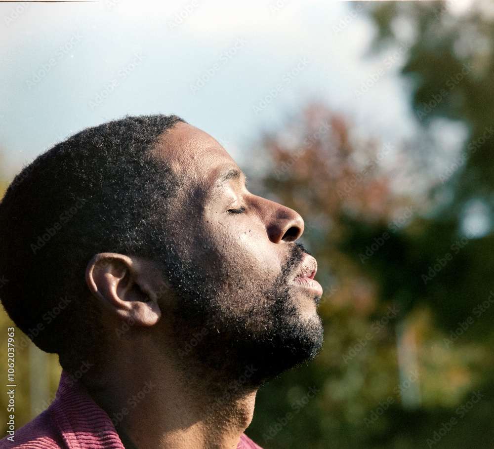 Serene man breathing fresh air in nature, enjoying sunlight with closed eyes Serene man breathing fresh air in nature, enjoying sunlight with closed eyes