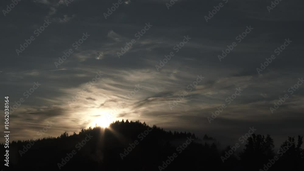 Dark sky over hill topped with trees becomes day as sun rises on amazing morning filled with fog rolling through and clouds passing by, time lapse. Dark sky over hill topped with trees becomes day as sun rises on amazing morning filled with fog rolling through and clouds passing by, time lapse.