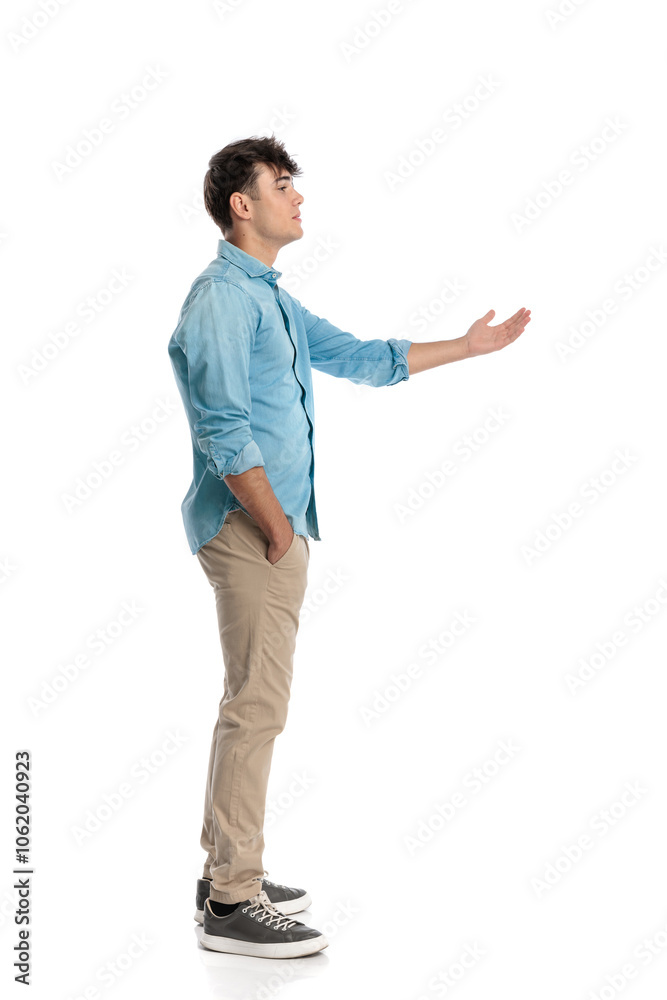 side view of young man standing in line with hand tucked in pockets side view of young man standing in line with hand tucked in pockets
