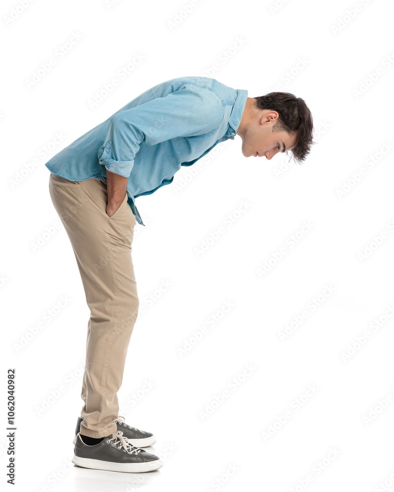 Naklejka premium young casual man leaning forward closely inspecting the floor