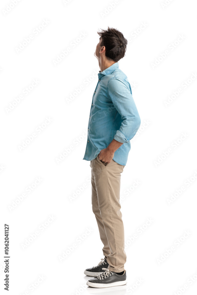 side view of young student with hands in pockets looking up side view of young student with hands in pockets looking up