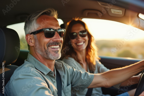 A candid photograph of two people enjoying a drive in a modern car, with a man driving and a woman in the passenger seat, showcasing a cheerful atmosphere.