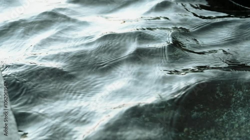 Water ripples with light reflection - shallow water surface texture, sunlight shining on natural clear blue water.