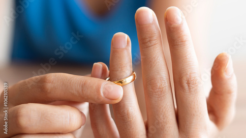 Human hand signing divorce contract, close-up. Wedding rings with marriage contract and judge gavel on a background