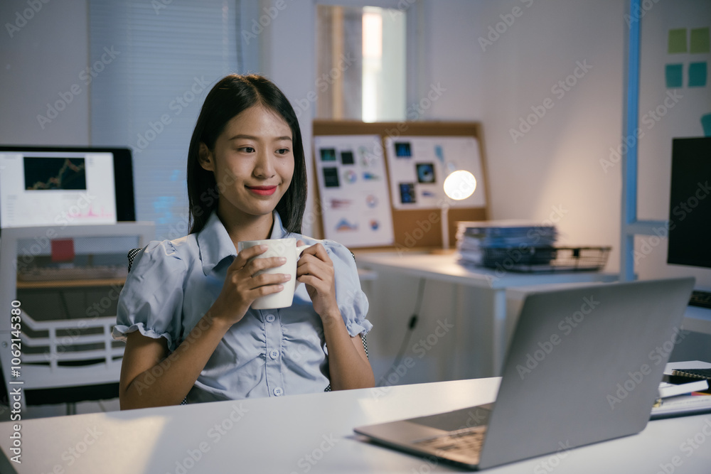 Young professional woman enjoying a cup of coffee while working on her laptop, focused on her tasks in a quiet office environment late at night Young professional woman enjoying a cup of coffee while working on her laptop, focused on her tasks in a quiet office environment late at night