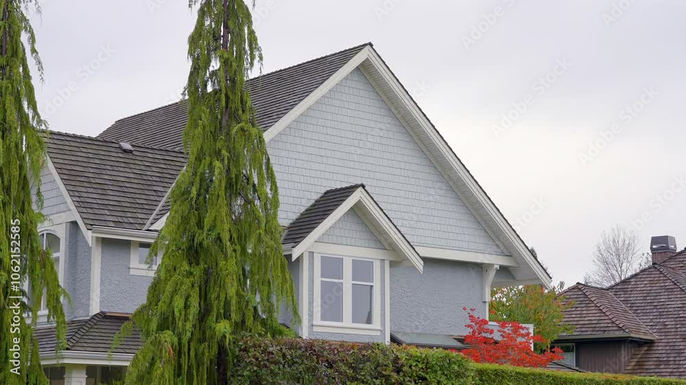 Establishing shot. Top of luxury house with big tree and nice landscape at fall rainfall in Vancouver, Canada, North America. Day time on October 2024. ProRes 422 HQ.