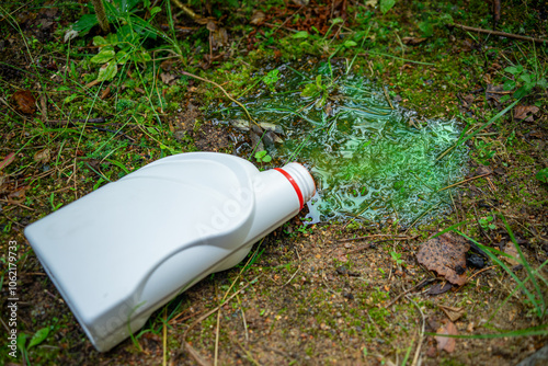 A spilled antifreeze canister.A poisonous liquid spilled on the ground.Pollution of the environment by motor oils.Green liquid on the grass. photo