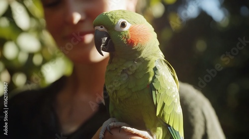 A woman holds a green parrot with red cheeks on her hand. photo