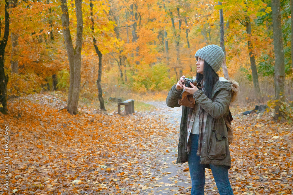 Naklejka premium Travel in nature. Young beautiful girl in autumn forest enjoys beauty of autumn nature, smiles. 