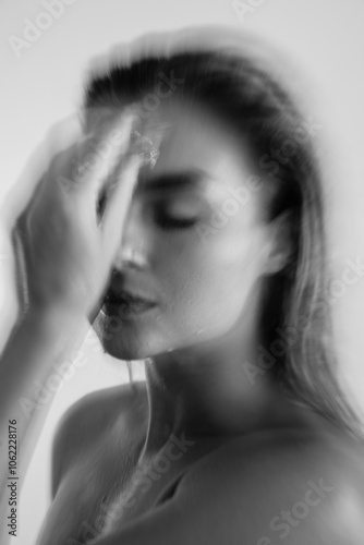 Creative shot with motion blur effect of young woman applying ice to her face