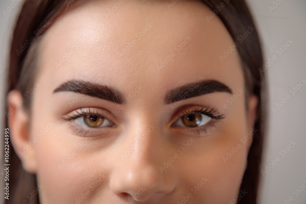 Beautician showing perfect eyebrows after permanent makeup treatment