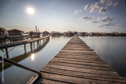 Wooden houses in the water. Holiday resort in the lake at sunset. Long wooden walkways lead to the individual houses. Landscape photo of the floating village of Bokodi, Lake Balaton, Hungary photo