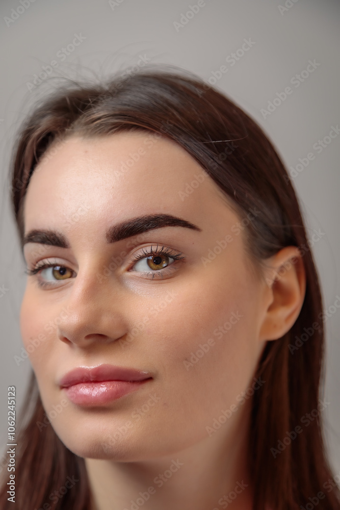 Portrait of beautiful young woman showing perfect eyebrows after microblading treatment
