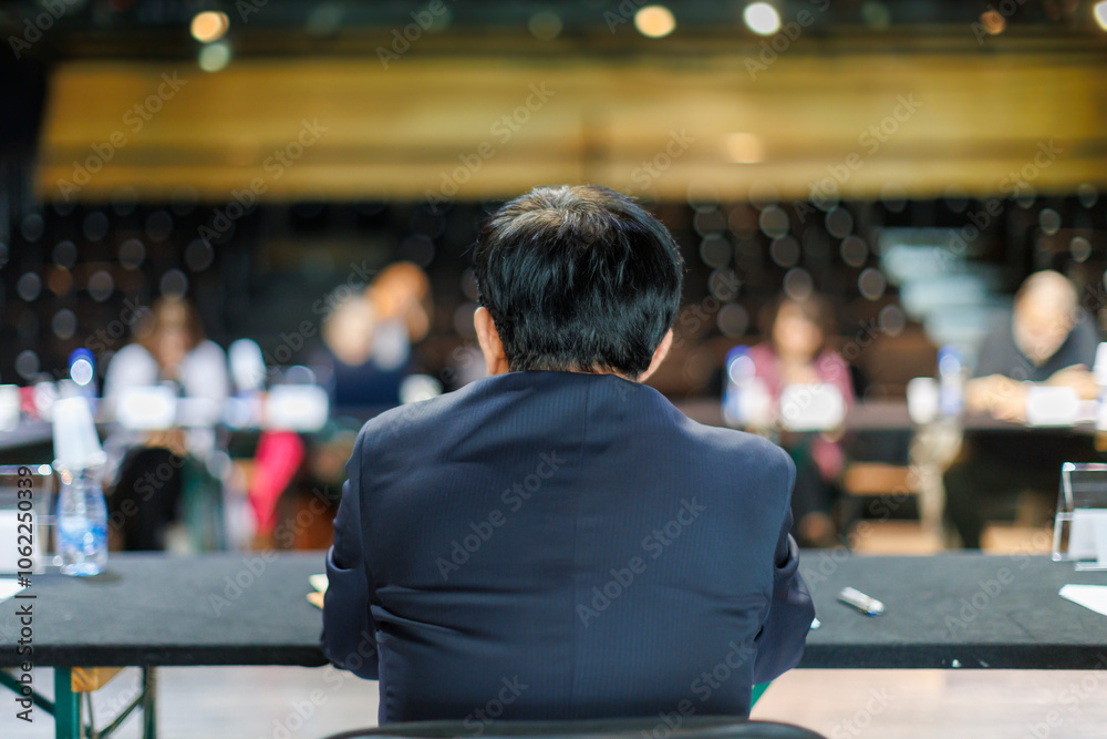 A speaker’s perspective at a panel discussion in a spacious auditorium with an attentive audience in the background A speaker’s perspective at a panel discussion in a spacious auditorium with an attentive audience in the background