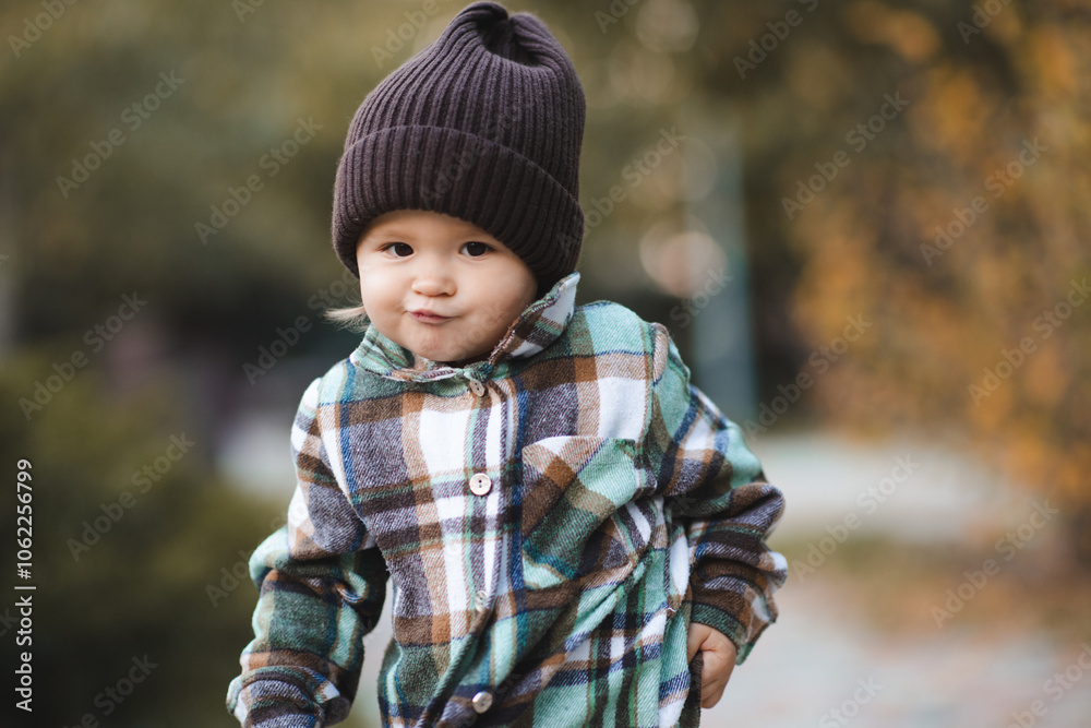 Funny baby girl 2-3 year old wearing knitted hat and checkered shirt walking in park outdoor. Autumn season. Funny baby girl 2-3 year old wearing knitted hat and checkered shirt walking in park outdoor. Autumn season.
