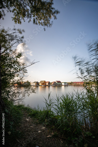 Wooden houses in the water. Holiday resort in the lake at sunset. Long wooden walkways lead to the individual houses. Landscape photo of the floating village of Bokodi, Lake Balaton, Hungary photo