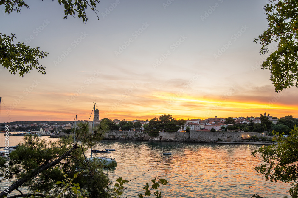 Coast, stone fortification of a harbor with sunset view. Landscape photo of the town of Krk, Croatia Coast, stone fortification of a harbor with sunset view. Landscape photo of the town of Krk, Croatia