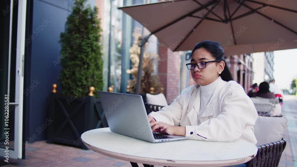 Young woman getting tired working on laptop in cafe