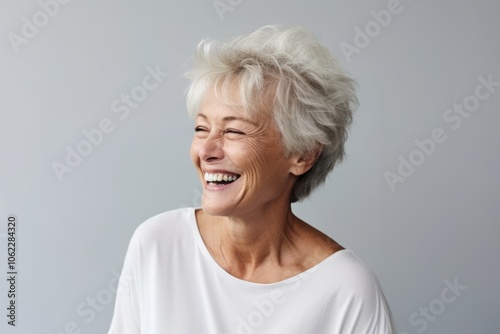 Portrait of a happy senior woman laughing and looking up over grey background