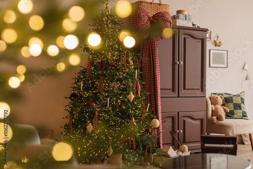 Illuminated Christmas tree next to a cupboard and wagon with wrapped Christmas gifts in a living room photo