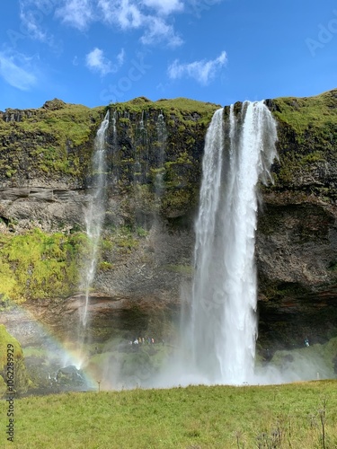 Seljalandsfoss waterfall in Iceland, cascading dramatically over a cliff. The powerful stream of water flows gracefully, framed by lush greenery and a stunning backdrop of rugged landscapes.