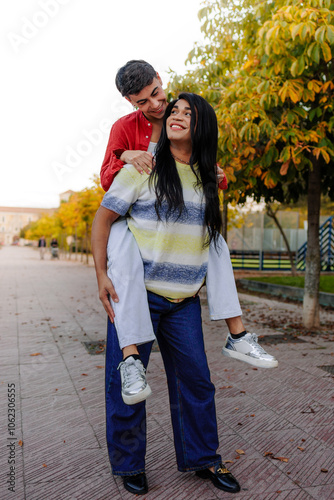 Latin trans woman piggybacking her girlfriend in a park