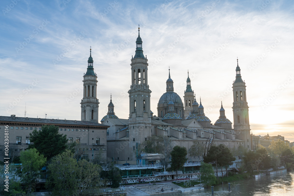 Illuminated Basilica del Pilar in Zaragoza, Spain, at dusk, with serene reflections on the Ebro River. Ideal for travel, architecture, and cultural themes. Illuminated Basilica del Pilar in Zaragoza, Spain, at dusk, with serene reflections on the Ebro River. Ideal for travel, architecture, and cultural themes.