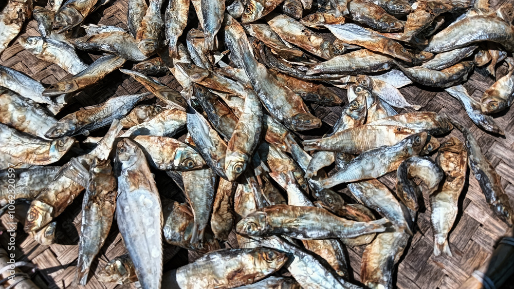 Salted fish being dried on a woven bamboo tray, showcasing texture and traditional details in food processing. Salted fish being dried on a woven bamboo tray, showcasing texture and traditional details in food processing.