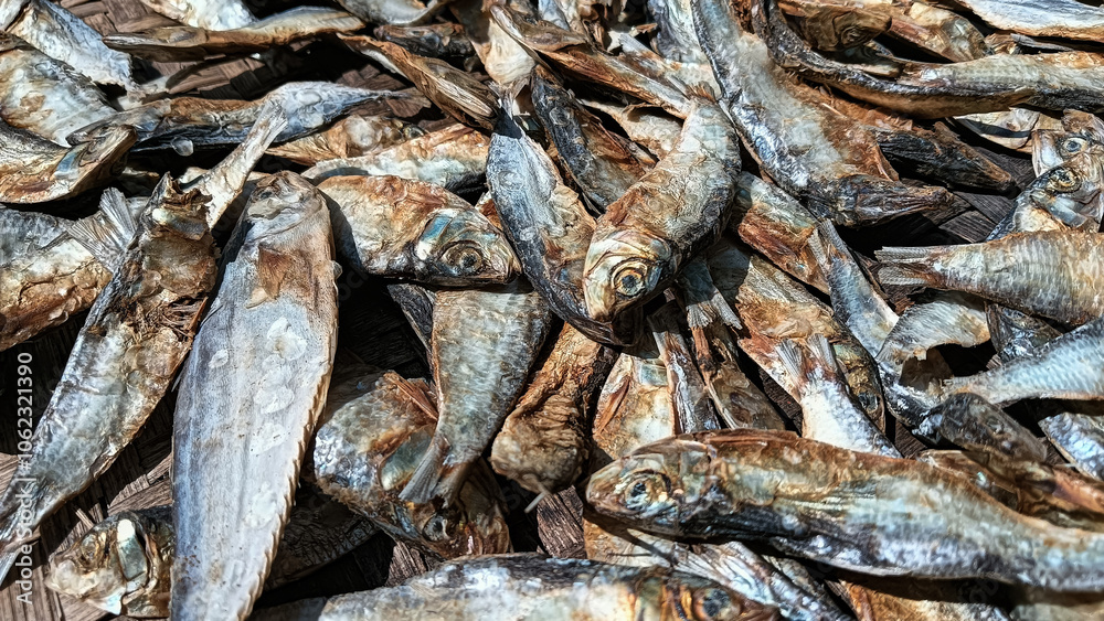 Salted fish being dried on a woven bamboo tray, showcasing texture and traditional details in food processing.