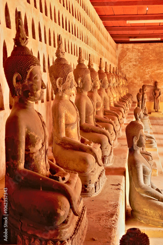 Many ceramic buddha statues, sculptures in different sizes lined up in a row in the cloister wall of Wat Si Saket, a buddhist temple in Vientiane, Laos