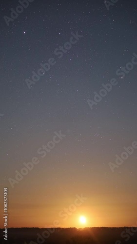Night sky transforming into sunrise with moon setting