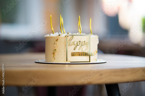 Soft focus. Delicious and stylish birthday cake adorned with candles and elegant gold lettering, perfect for celebrations.