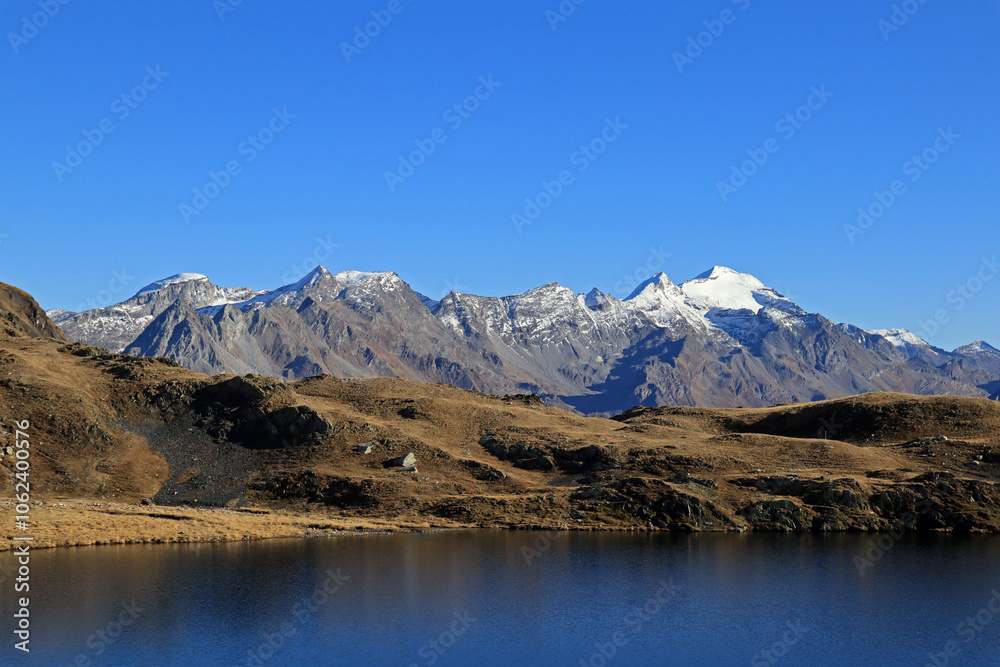 Naklejka premium Alpine lake with Adula glacier in the background on a beautiful autumn day