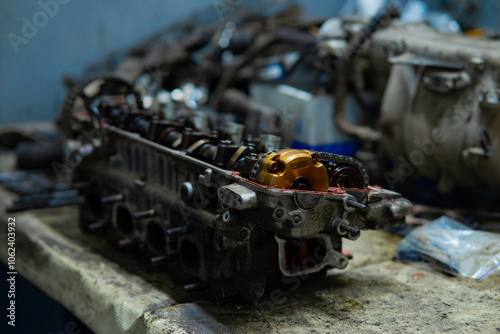 Disassembled cylinder head resting on a mechanic's workbench, highlighting intricate details and precision engineering.