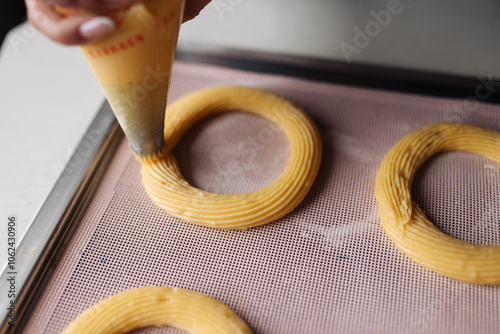 Piping choux pastry with a piping bag for making cream puff rings