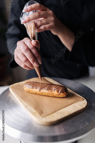 Woman pastry chef decorating chocolate eclair