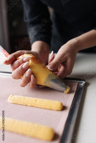 Squeeze the dough out of the pastry bag o nto a baking tray for baking eclairs.