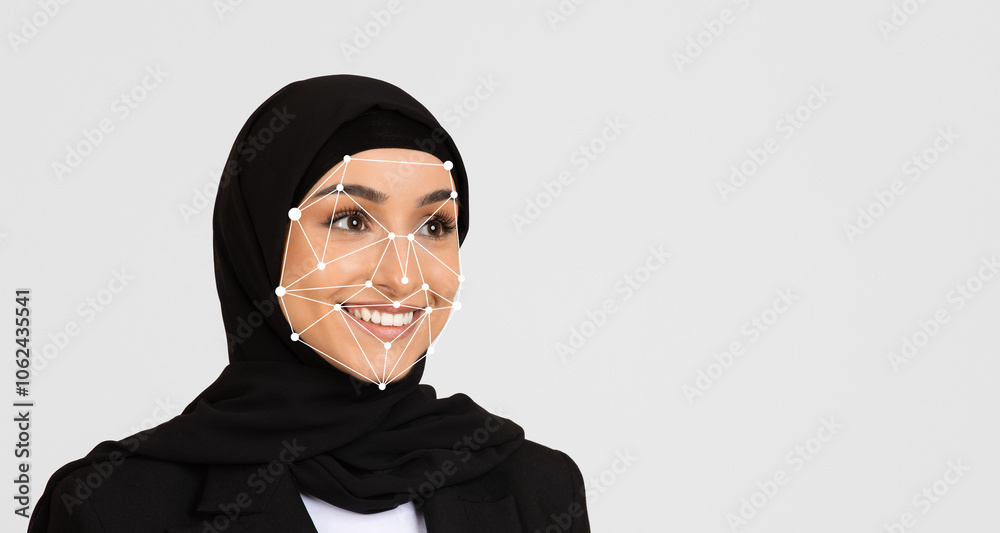 A woman wearing a black hijab smiles while participating in a technology event, where facial recognition technology is demonstrated. The setting highlights advancements in digital innovation. A woman wearing a black hijab smiles while participating in a technology event, where facial recognition technology is demonstrated. The setting highlights advancements in digital innovation.