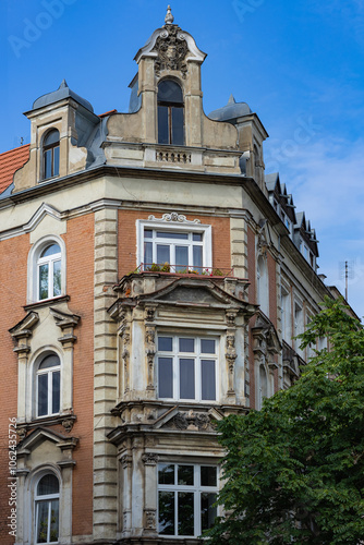 Historic European building facade with intricate architectural details, vintage windows and a beautifully preserved corner design under a bright blue sky. Heritage and classic architecture