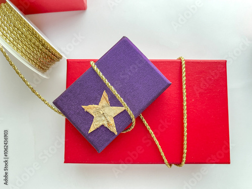 Christmas gift box red and pruple with star deco packaging with golden ribbon roll, on white background, copy space photo