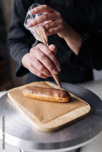 Woman pastry chef decorating chocolate eclair
