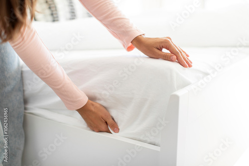 Woman putting white fitted sheet over new mattress on bed, closeup shot. Household chores concept
