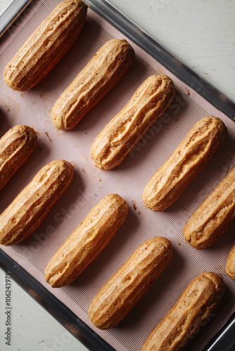 golden brown eclairs on a pink baking sheet
