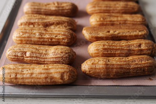 golden brown eclairs on a pink baking sheet
