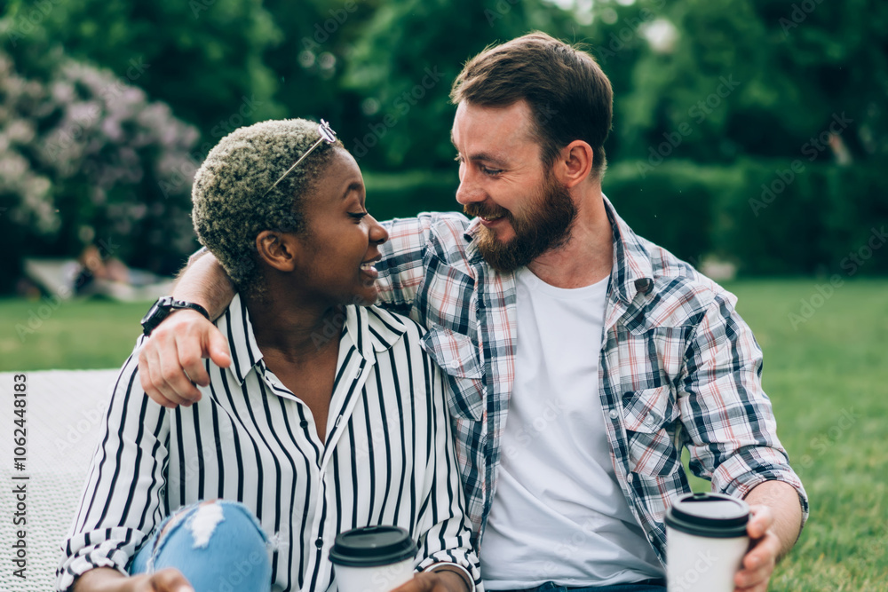 Multiracial couple with coffee in park chatting happily Multiracial couple with coffee in park chatting happily