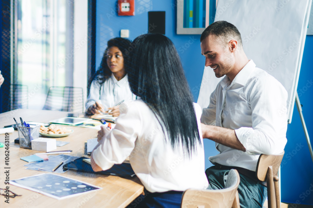 Obraz premium Considerate multiethnic colleagues discussing graphs while sitting in office