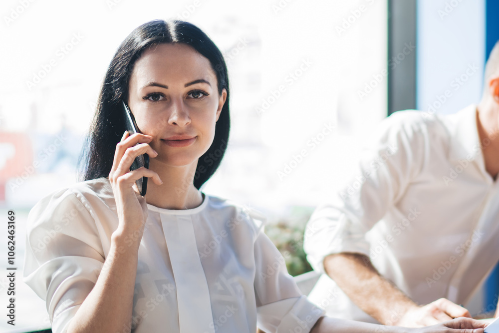 Confident elegant businesswoman phoning while sitting at table in office Confident elegant businesswoman phoning while sitting at table in office