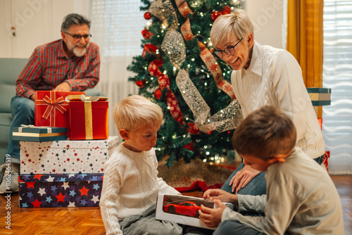 Two brothers opening presents on christmas morning with family photo