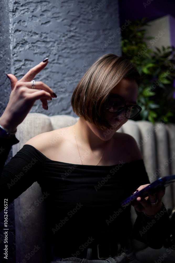 Obraz premium A Stylish Young Woman Enjoying Herself in a Nightclub while Engaging with Her Phone