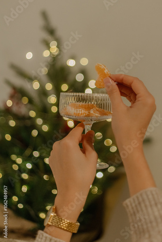 person with christmas tree and glass of tangerines